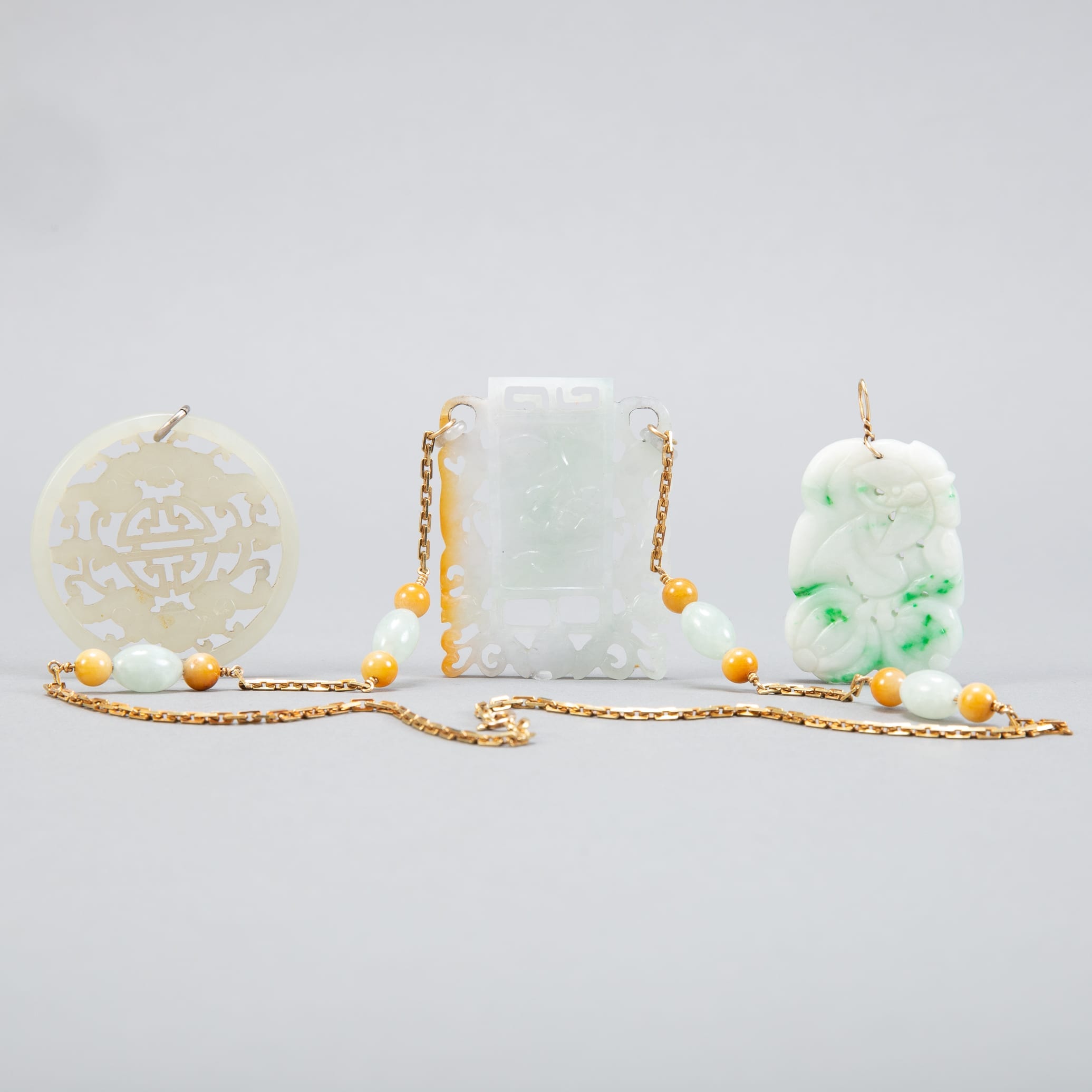 Lot 202: Grp:3 20th c. Chinese Pale Jade Pendants - Gold