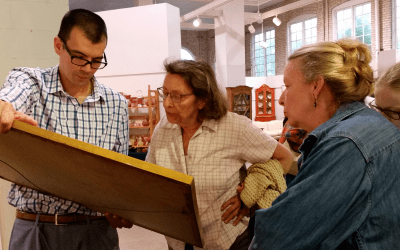 Auction specialists reviewing a framed artwork with clients at an appraisal event