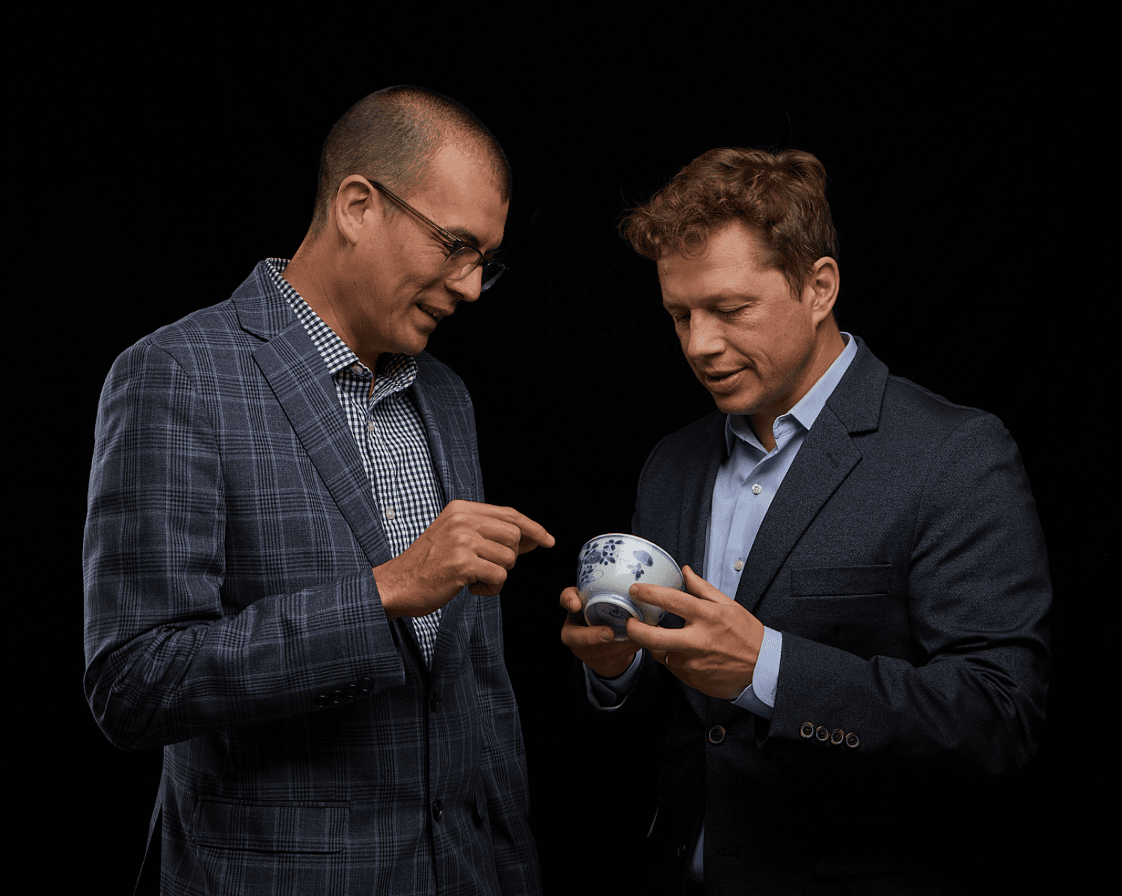Auction specialists examining a Chinese blue-and-white porcelain vessel
