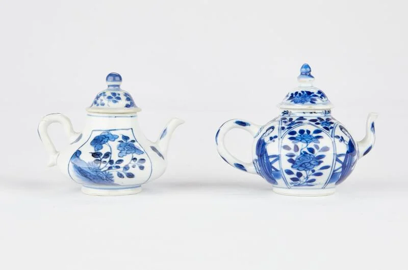 2-porcelain-teapots-blue-white Two antique Chinese blue and white porcelain teapots featuring intricate floral and landscape panels.