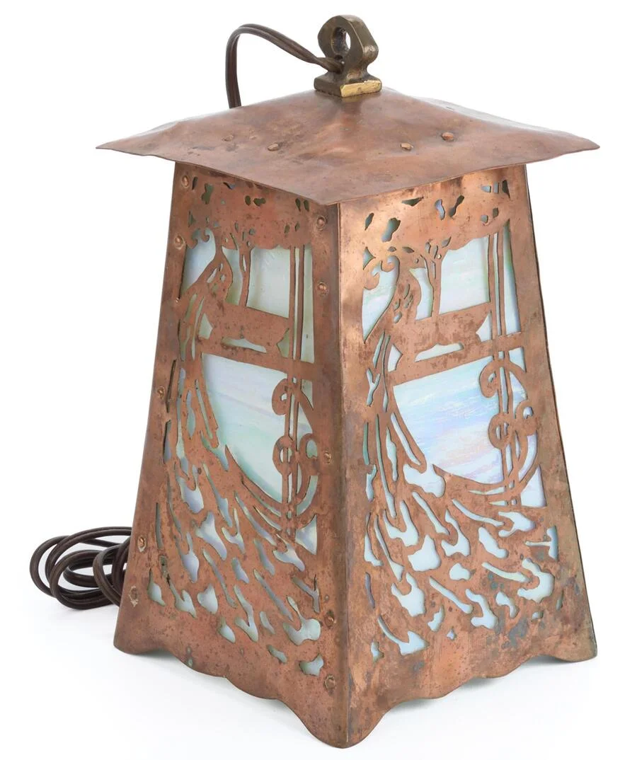 handicraft-pierced-copper-peacock-lantern-side Handcrafted Arts and Crafts copper lantern featuring a pierced peacock design with iridescent glass panels and Art Nouveau detailing pictured at an angle.